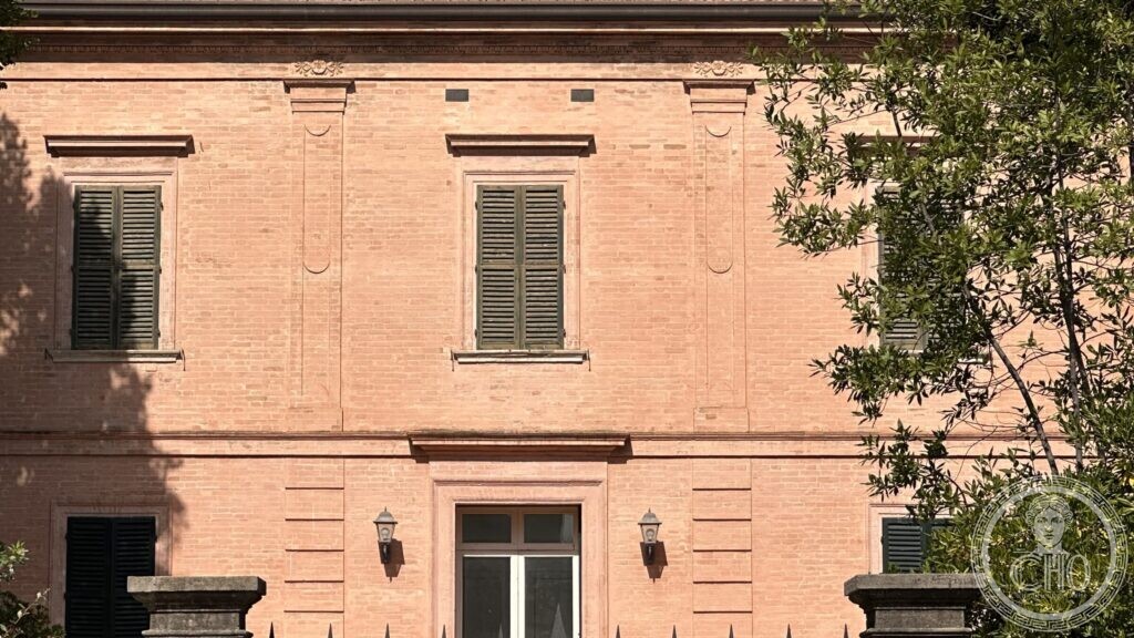 Detail of the pink rendered facade with flat pilaster strips, recessed panels and carved rosettes