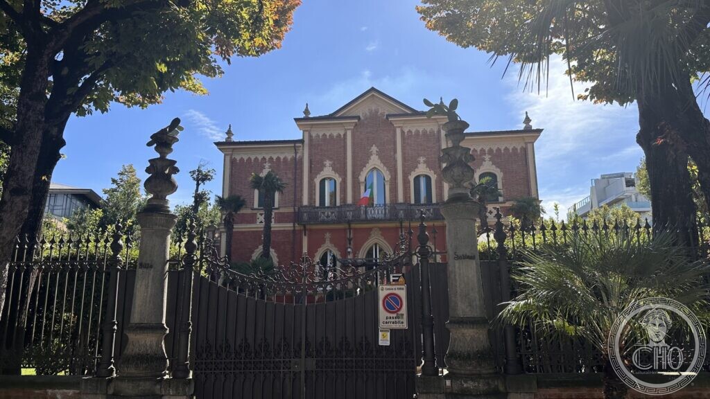 Villa Solinas seen through the iron railing, with two tall carved stone pillars in front