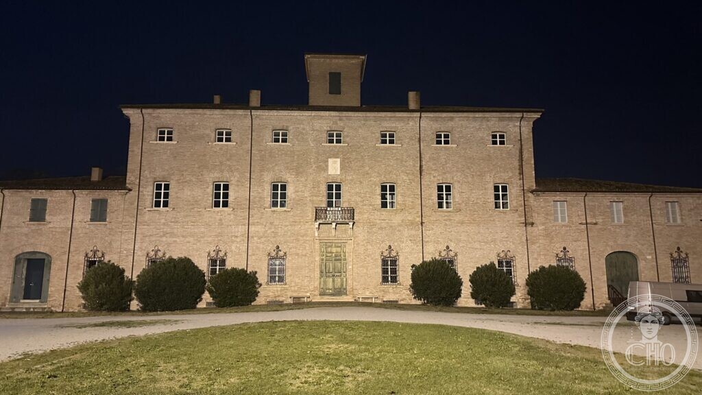 The three-storey stone façade of Villa Torlonia lit at night, with a balcony over the central door