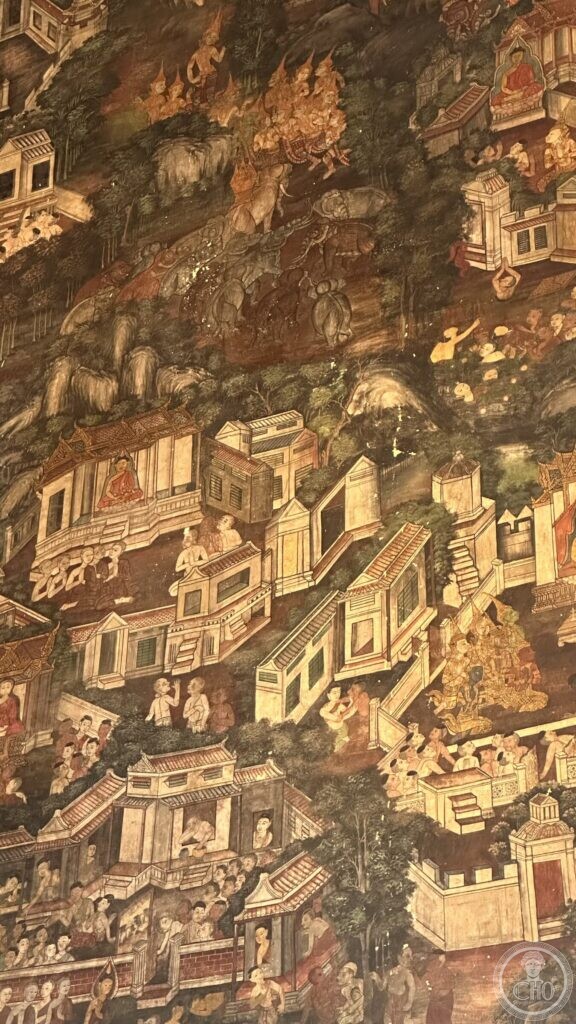 Detail of a Wat Suthat mural showing elephants with riders crossing a hillside above a town of pavilions and monks