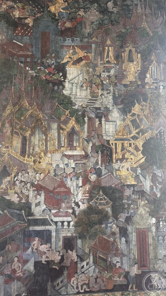 Detail of a Wat Suthat mural showing a dense painted city of gilded roofs, courtyards and crowds