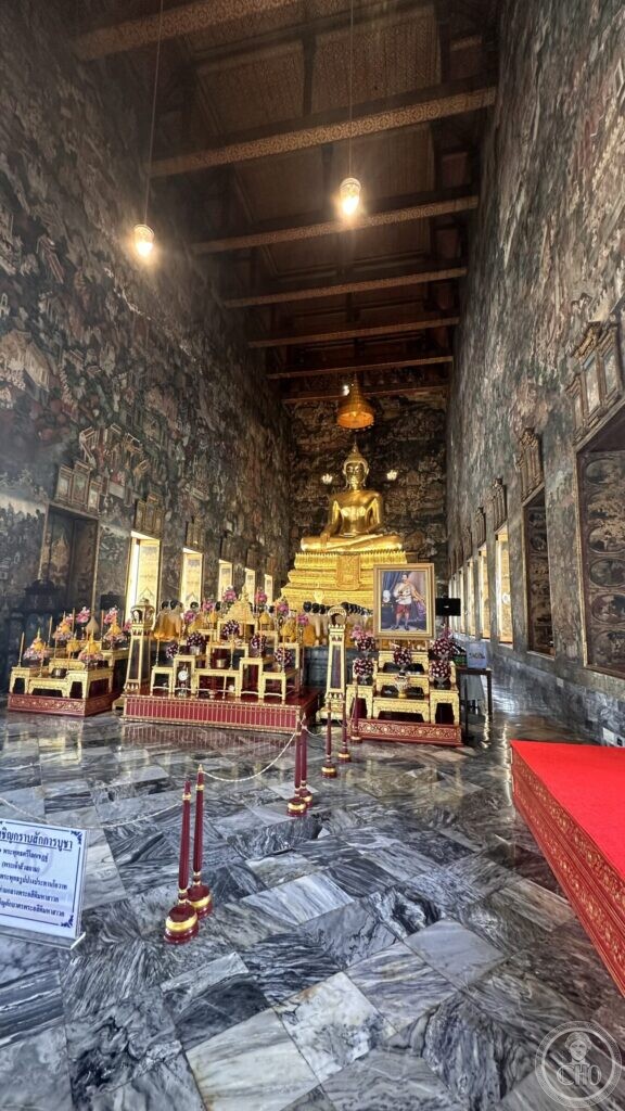 The full length of the ordination hall at Wat Suthat, painted from floor to ceiling, with the altars and the gilded image at the far end