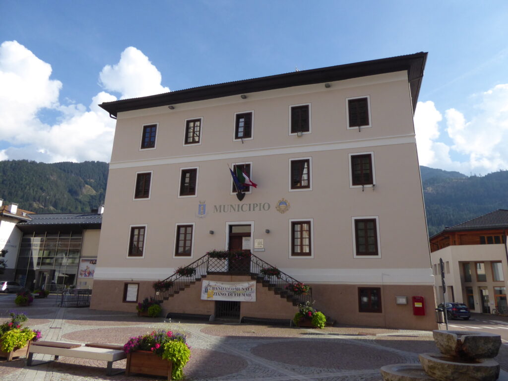 Traditional stone and timber town hall of Ziano di Fiemme against Dolomite peaks