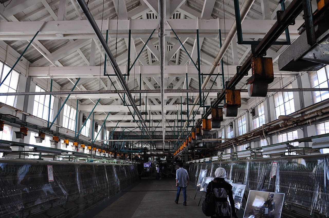 Interior of the Tomioka Silk Mill reeling hall showing rows of mechanical silk-reeling machines in the brick building, Gunma Prefecture