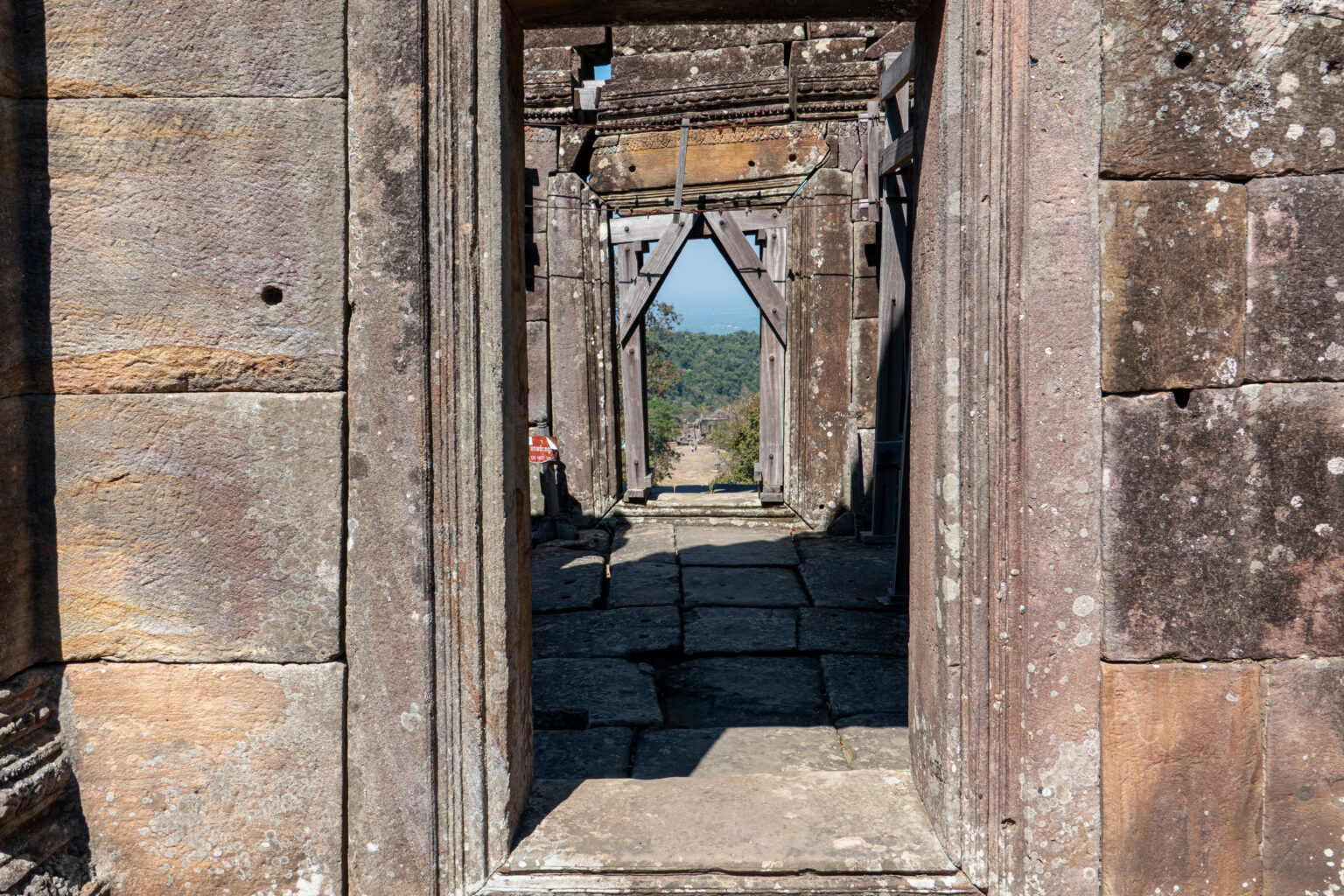 View through a stone doorway of the temple out over the Cambodian plain far below the escarpment