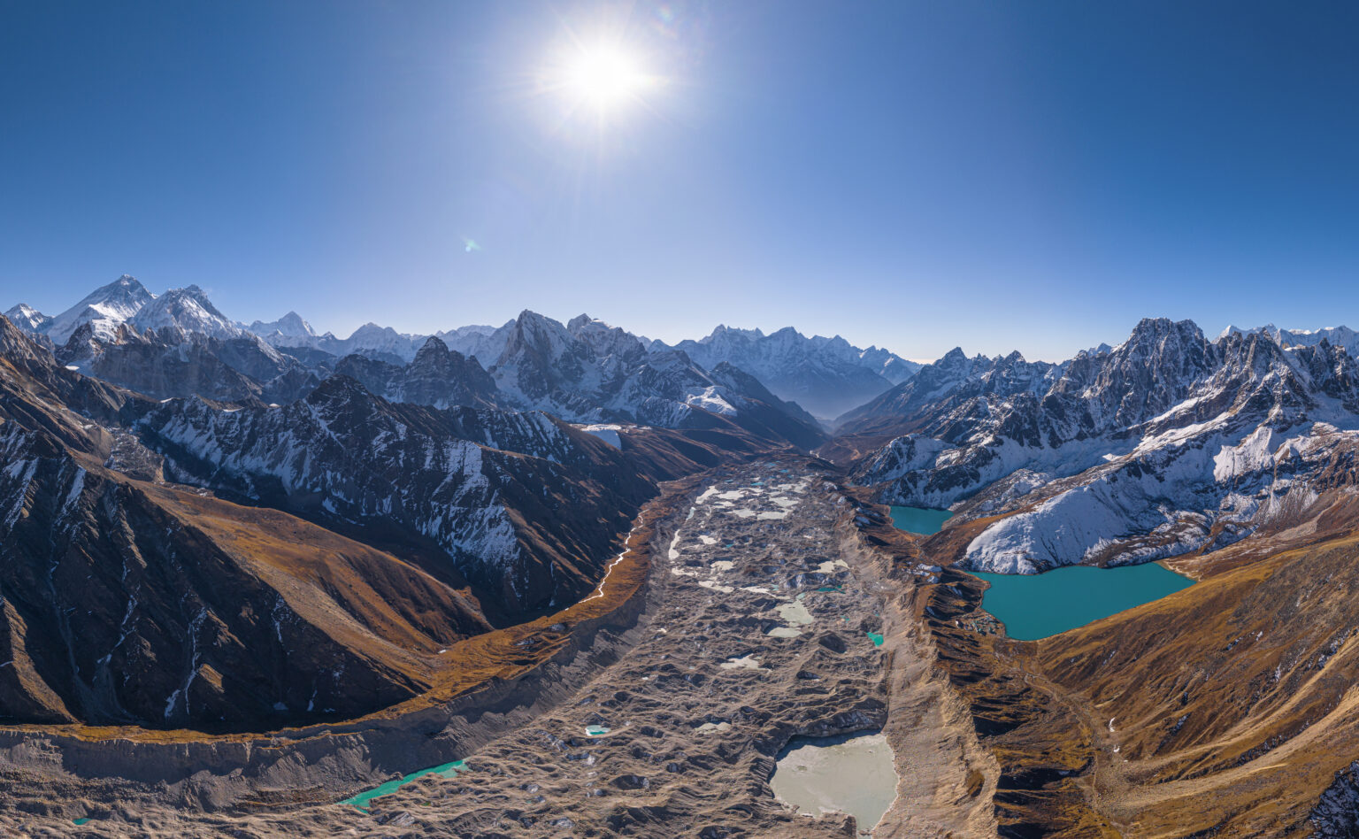 Aerial view of the Ngozumpa glacier, its grey surface pitted with meltwater pools between mountain ridges