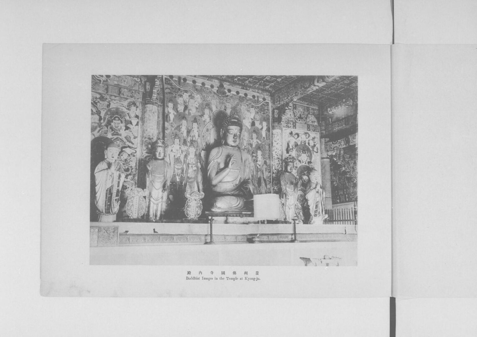An old printed plate showing the seated Buddha of Seokguram inside the rotunda, with carved attendant figures on the wall behind