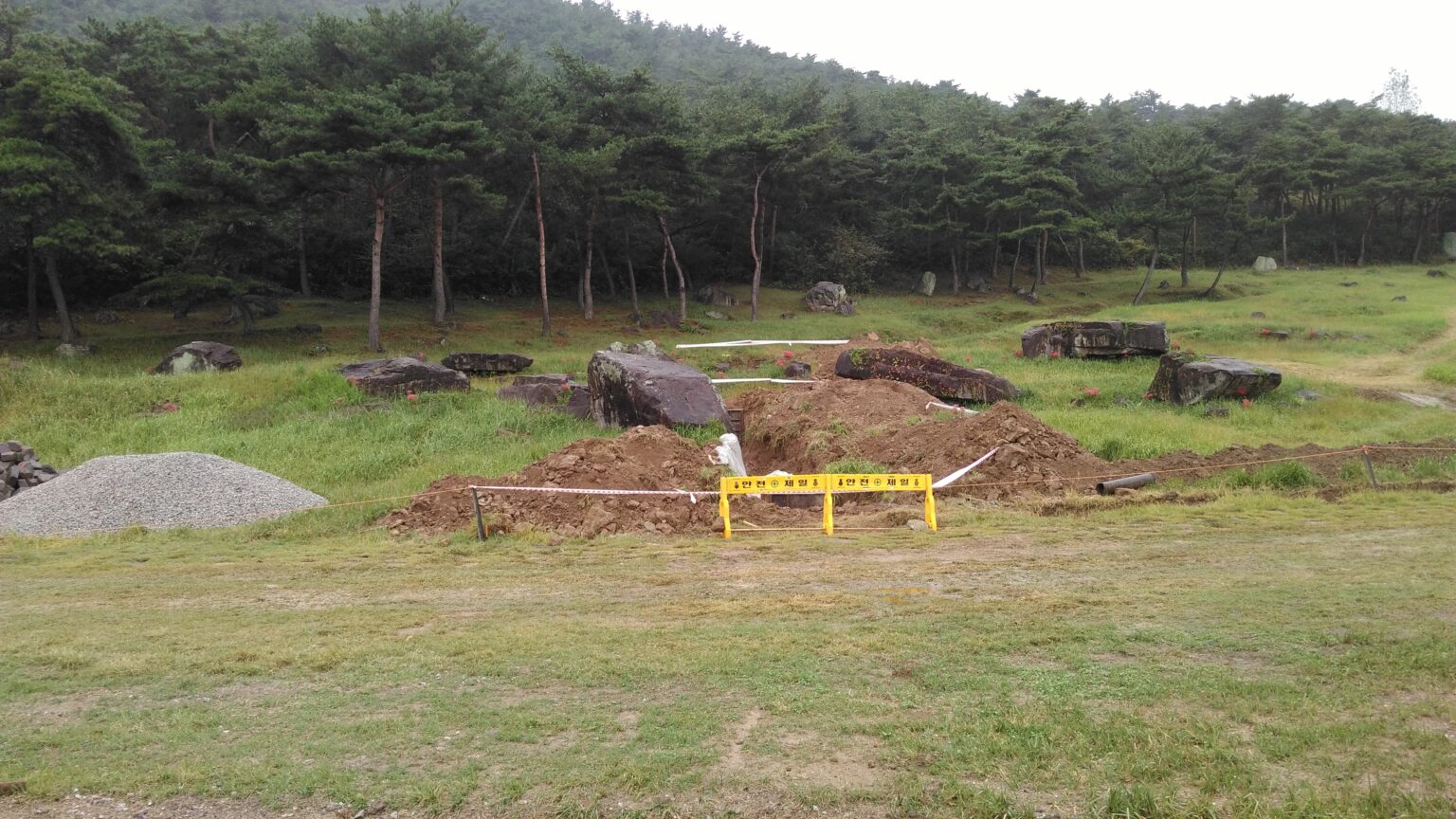 Bare earth, a yellow barrier and modern works beside the dolmens at Gochang