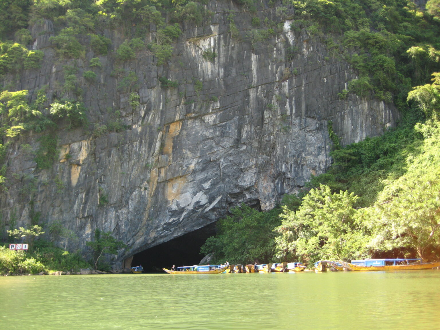Forested limestone cliffs rising above the green water of a river in Phong Nha-Ke Bang