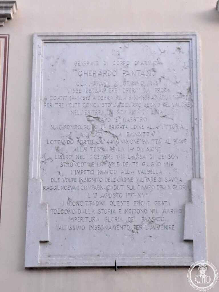 A large white marble plaque in a moulded frame on a pale wall, closely covered with an incised inscription in capitals