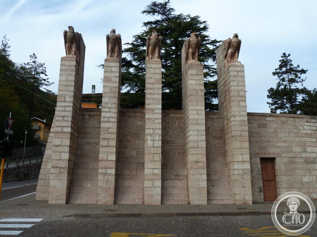 Frontal view of the five pillars with eagle statues and lower sloping buttresses behind them.