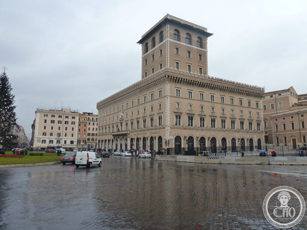 The tower and front of Palazzo Venezia seen from the north side of the square, a Christmas tree and cars on the wet pavement