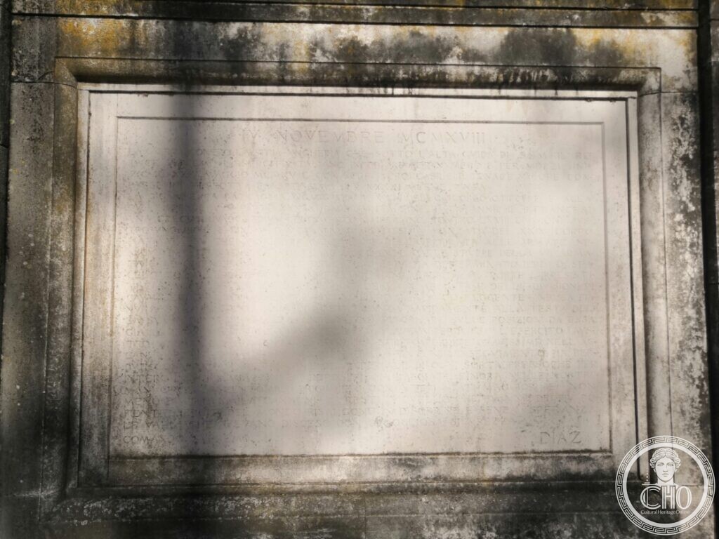 A weathered stone plaque in a moulded frame carrying a long inscription headed IV Novembre MCMXVIII and signed Diaz