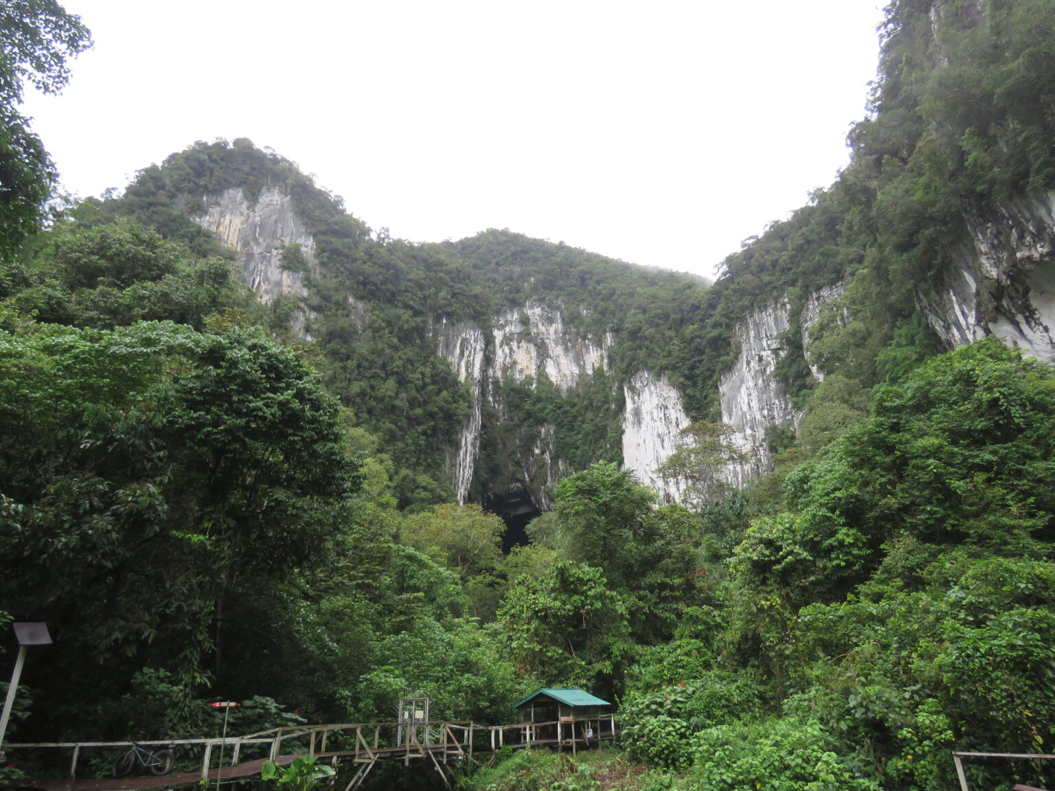 Pale limestone cliffs rising above dense rainforest, with a walkway at their foot