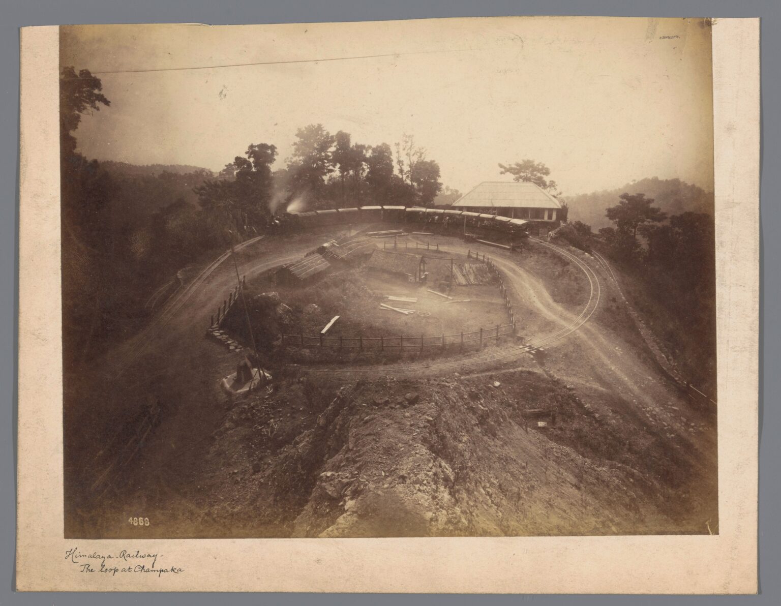 An old sepia photograph of a mountain railway curving back on itself across a bare hillside