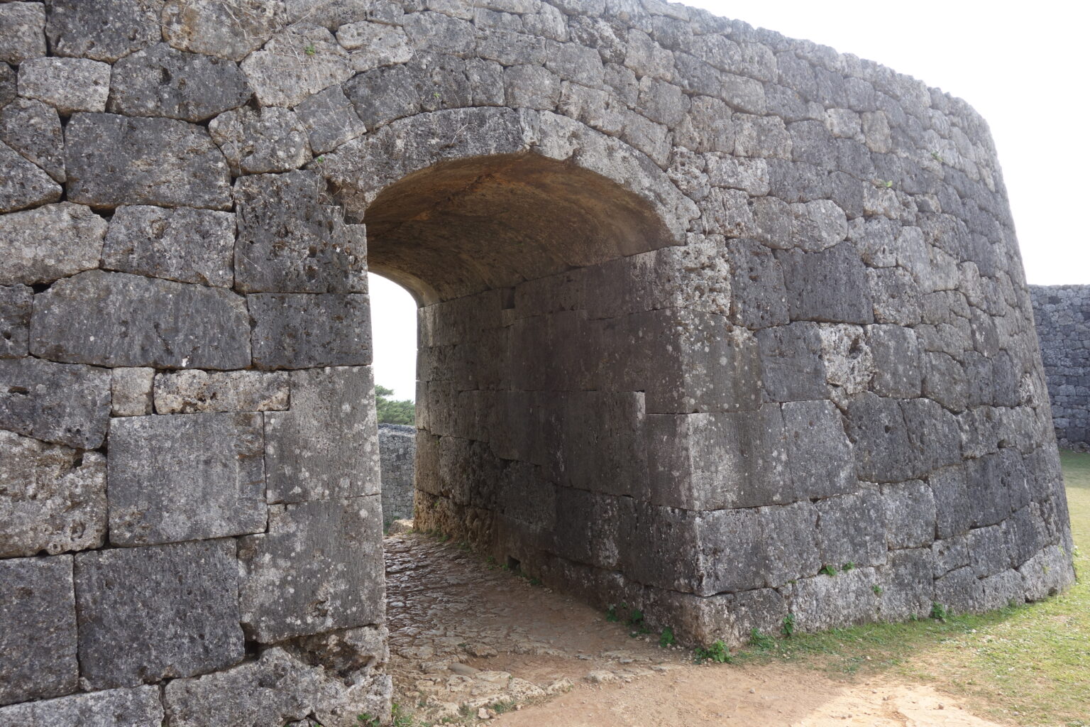 A tunnel-like gateway cut through a thick wall of fitted limestone blocks